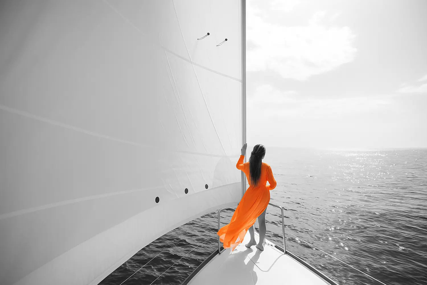 woman on sail boat looking out at water with orange dress
